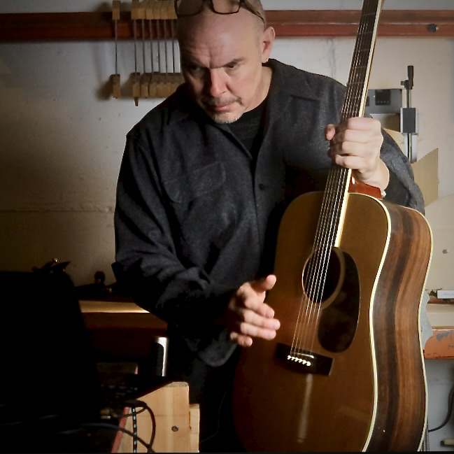Rick Molloy working with a guitar in the shop.